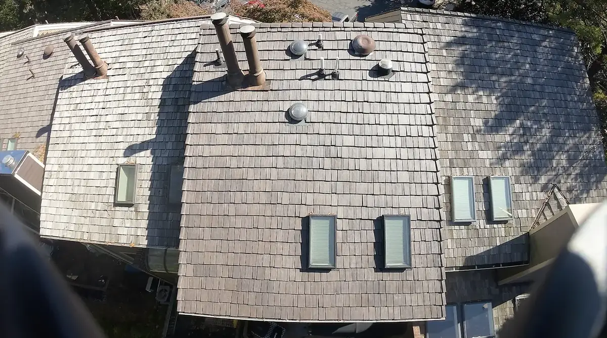 Aerial view of an aged cedar shake roof with chimney pipes, vents and skylights